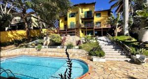 a swimming pool in front of a yellow building at Pousada Oceanica Buzios in Búzios