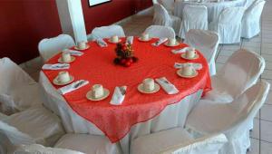 einen Tisch mit weißen Stühlen und einem roten Tischtuch in der Unterkunft Hotel Marina Topolobampo in Topolobampo