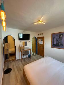 ein Schlafzimmer mit einem Bett und einem Schreibtisch mit Computer in der Unterkunft USHA Guest House in Chefchaouen