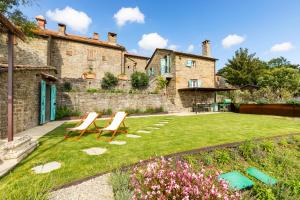 a garden with two benches in front of a building at Relais Tosca in Cortona