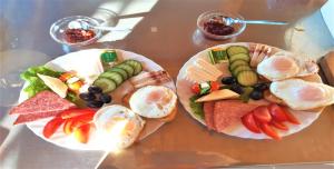 two plates of food with eggs and vegetables on them at Pensiunea Esential in Ocnele Mari