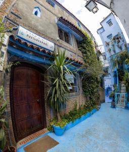 a building with a door and a plant in front of it at Hotel Nisrine in Chefchaouen