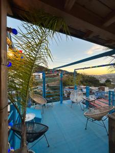 eine Terrasse mit Stühlen und Tischen auf einem Dach in der Unterkunft USHA Guest House in Chefchaouen