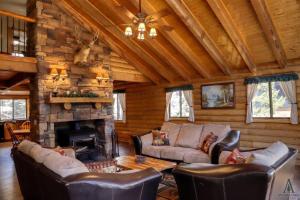 a living room with leather furniture and a stone fireplace at Rustic Mountain Log Cabin with Fire Pit in Duck Creek Village