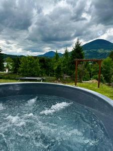 a hot tub filled with water with mountains in the background at Rivera Cabin in Colibiţa