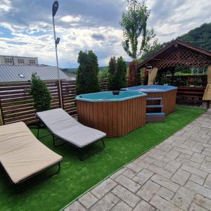 a backyard with a hot tub and two chairs on grass at Pensiunea Esential in Ocnele Mari