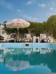 a swimming pool with two chairs and an umbrella at Villa Shell in Zatoka