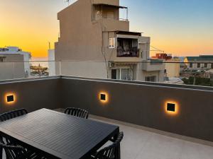 a table and chairs on a balcony with the sunset at City Breeze Suites in Heraklio