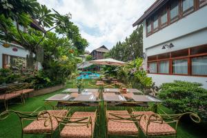 an outdoor dining table with chairs and an umbrella at Kodchasri Thani Heritage Collections in Chiang Mai