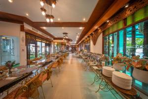 a restaurant with tables and chairs and windows at Kodchasri Thani Heritage Collections in Chiang Mai
