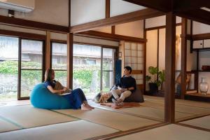 two people sitting on the floor in a room at 錆と煤 sabitosusu INN-prema- in Aki