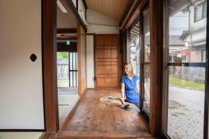 a woman standing in the hallway of a house at 錆と煤 sabitosusu INN-prema- in Aki