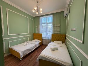 two beds in a room with green walls and a window at Mayden Tower apartment in Baku