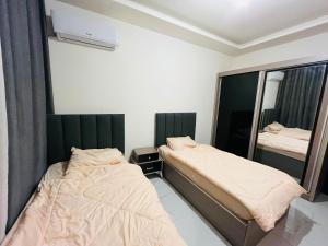 two beds in a room with a mirror at شقة أنيقة-غرفتين وصالة مع بلكونة Stylish 2-Bedroom Apartment with Balcony in Amman