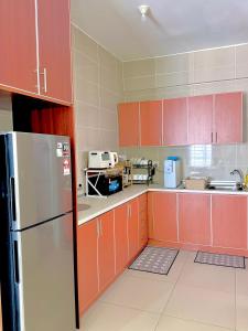a kitchen with orange cabinets and a refrigerator at Singgah homestay saujana aster in Putrajaya