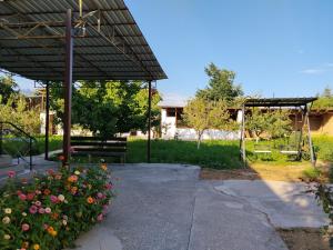 a pavilion with a bench and flowers in a garden at OMKA Guest House in Toktogul