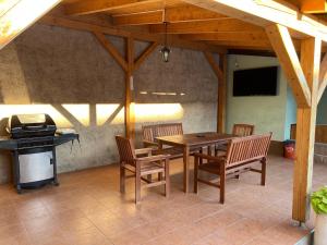 a patio with a table and chairs and a grill at Apartmán se společným bazénem Zlonice in Zlonice