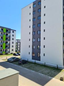 a large white building with cars parked in a parking lot at Cristina Home in Alba Iulia