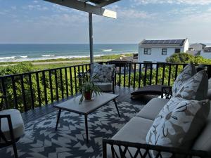 a patio with chairs and a table and the ocean at Seaview Sunsets in Gqeberha