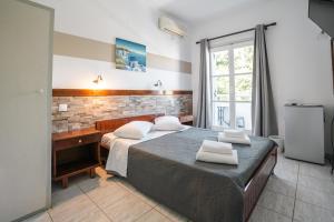 a bedroom with a bed and a desk with towels at Narkissos Hotel in Kamari