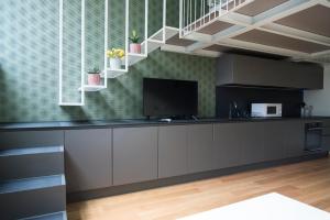 a kitchen with grey cabinets and a flat screen tv at Youhosty - Lambro12 in Milan