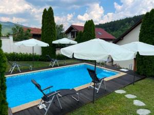 a swimming pool with chairs and umbrellas next to a house at U Izhu with Private Pool, Sauna & BBQ in Prevala