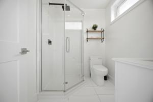 a white bathroom with a shower and a toilet at Exquisite, Bright & Modern Condo - Free Parking in Niagara Falls +41 photos