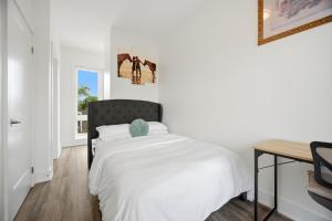 a white bedroom with a bed and a desk at Exquisite, Bright & Modern Condo - Free Parking in Niagara Falls