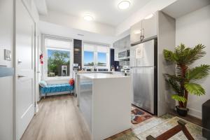 a kitchen with white cabinets and a refrigerator at Exquisite, Bright & Modern Condo - Free Parking in Niagara Falls