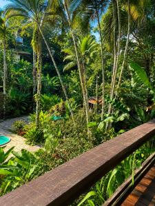 a wooden bench in front of a garden with palm trees at Recanto Serenare in Angra dos Reis