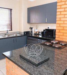 a kitchen with blue cabinets and a black counter top at Modern 2 bedroom at Waterfall Ridge-Midrand in Midrand +12 photos