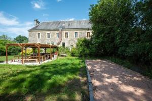 a large stone house with a picnic table in front of it at Ferme du ru paisible in Tournières