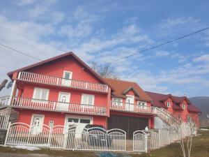a red house with a white fence in front of it at Apartman DANE in Štikada