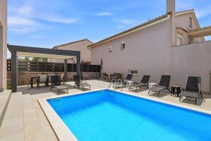a swimming pool with chairs and a table and a house at House Green in Vrh