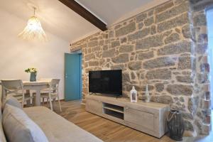 a living room with a tv and a stone wall at Stazzo Rosalba in Arzachena