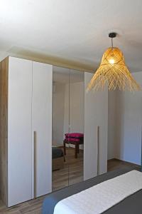 a bedroom with a white cabinet and a chandelier at Stazzo Rosalba in Arzachena