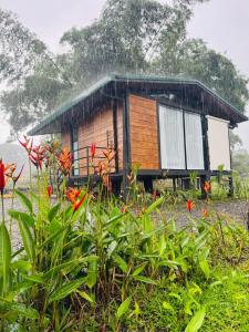 a small wooden house in a field with flowers at Cabañas La Hermosa #1 in Guápiles