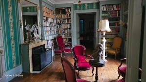 a living room with chairs and a fireplace and bookshelves at Chambre Napoléon III in Fleuriel