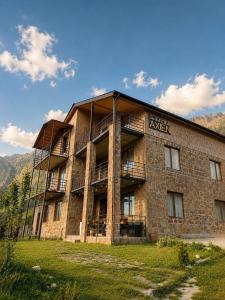 ein großes Backsteingebäude mit einem Schild darauf in der Unterkunft Hotel Axien Kazbegi in Kazbegi