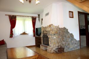 a living room with a stone fireplace and a tv at Domki w Bieszczadach in Polańczyk