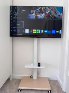 a flat screen tv hanging on a wall with a table at Historic High St Flat with Peaceful Garden Retreat in Stony Stratford