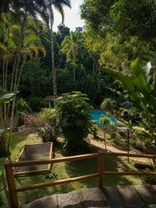 a wooden fence in front of a garden with a pool at Recanto Serenare in Angra dos Reis