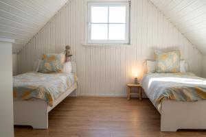 a attic bedroom with two beds and a window at Skandi Design Ferienhaus mit Hafenblick & Beach in Wandlitz