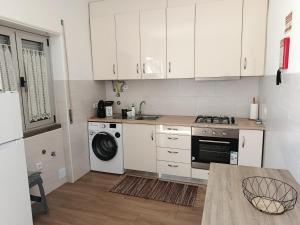 a kitchen with white cabinets and a washer and dryer at Casa da Avó Laurinda in Valado dos Frades
