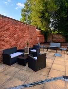 a patio with chairs and tables and a brick wall at Historic High St Flat with Peaceful Garden Retreat in Stony Stratford