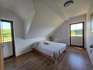 a white bedroom with a bed and two windows at Agroturystyka u Kasi in Suryty