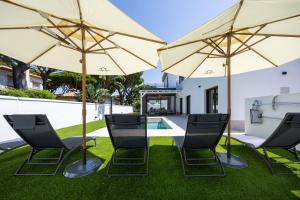 a group of chairs and umbrellas next to a pool at Fely Sea Villa in Novo Sancti Petri