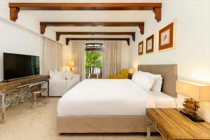 a bedroom with a large white bed and a television at Village du Pecheur in Baie Sainte Anne