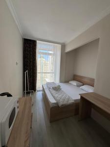 a bedroom with a bed and a tv and a window at Уютные комнаты-студии in Astana