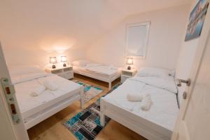 a bedroom with two beds and two tables with lamps at Golden Lake House in Konjic